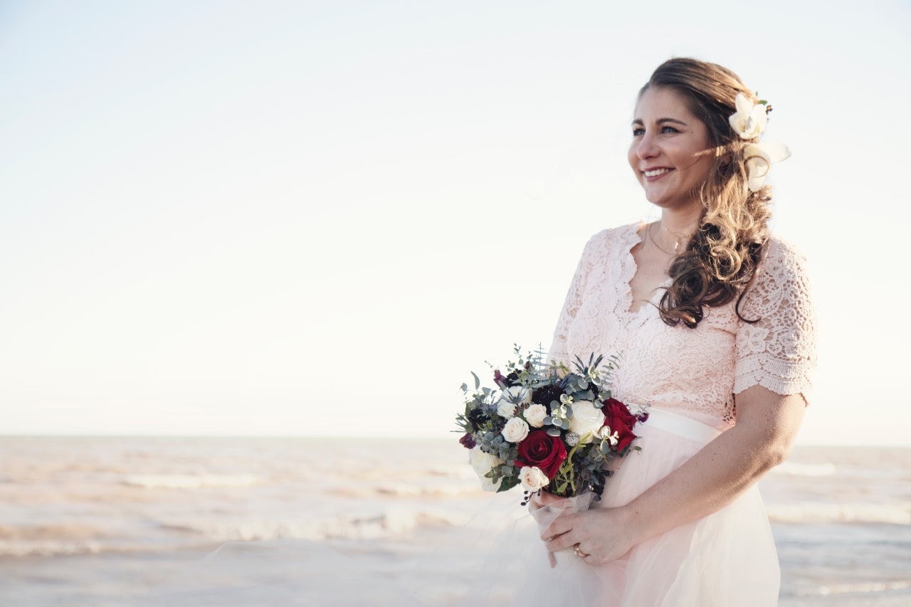 A bride holding a jewel-toned bouquet while standing outside.