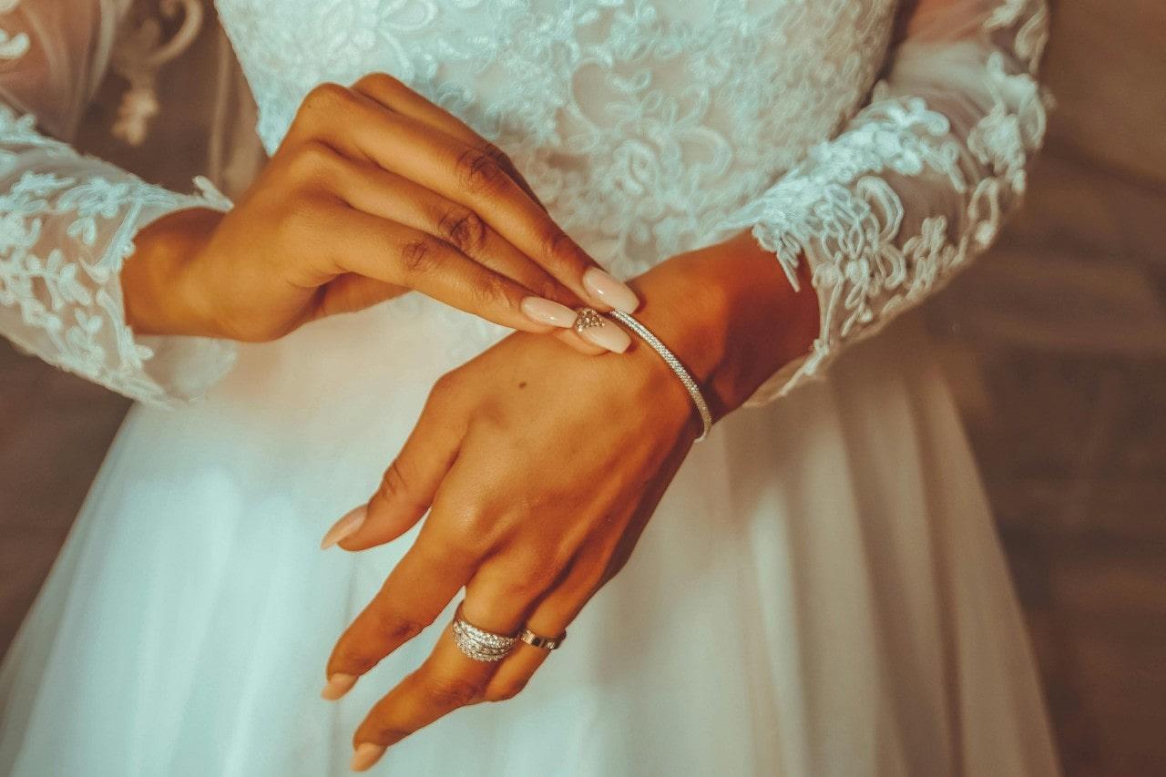 a bride in a wedding dress putting on a silver diamond bracelet