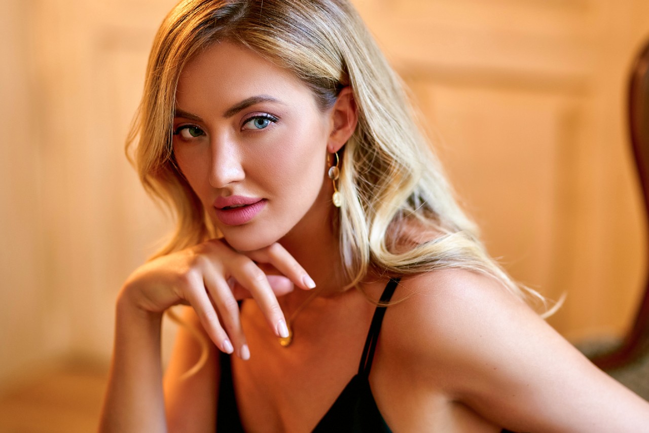 A woman with blond hair showcasing a drop yellow gold earring gazing at the side