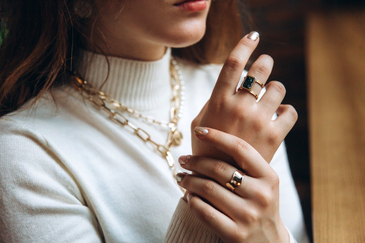 A woman in a white turtleneck in a yellow gold bold chain jewelry