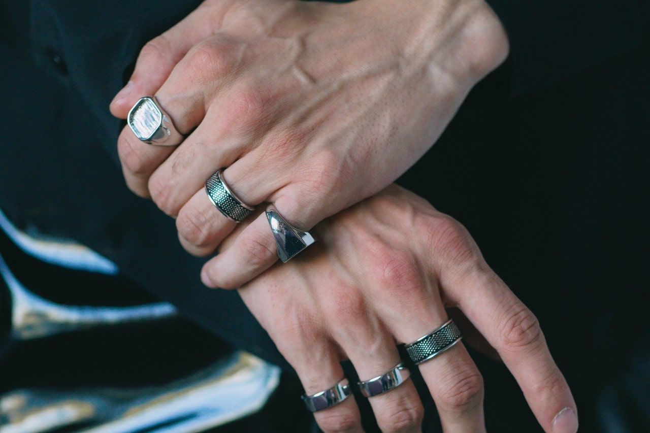 a pair of hands wearing bold, silver statement rings