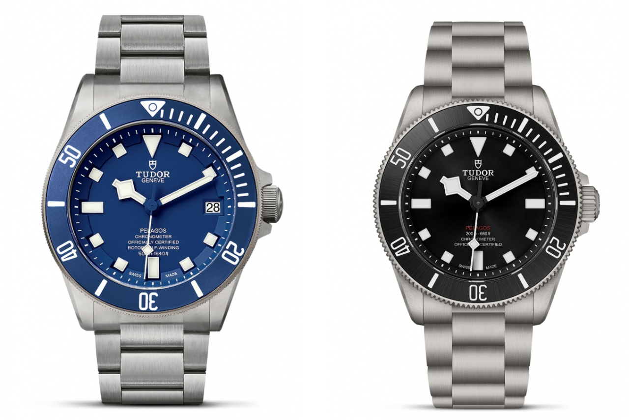 Two metallic TUDOR watches, one with a deep blue dial, and the other with black.