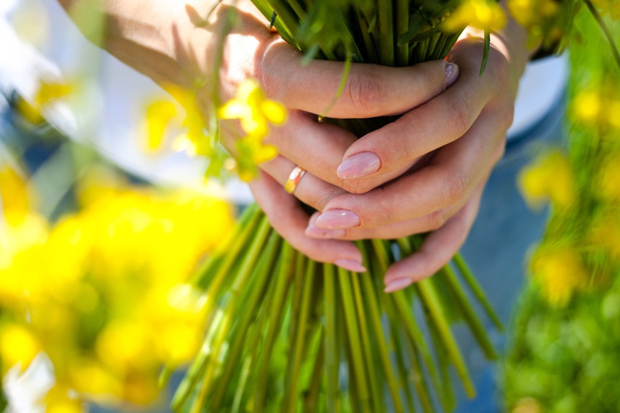 a bride holding her bouquet and wearing a yellow gold wedding band