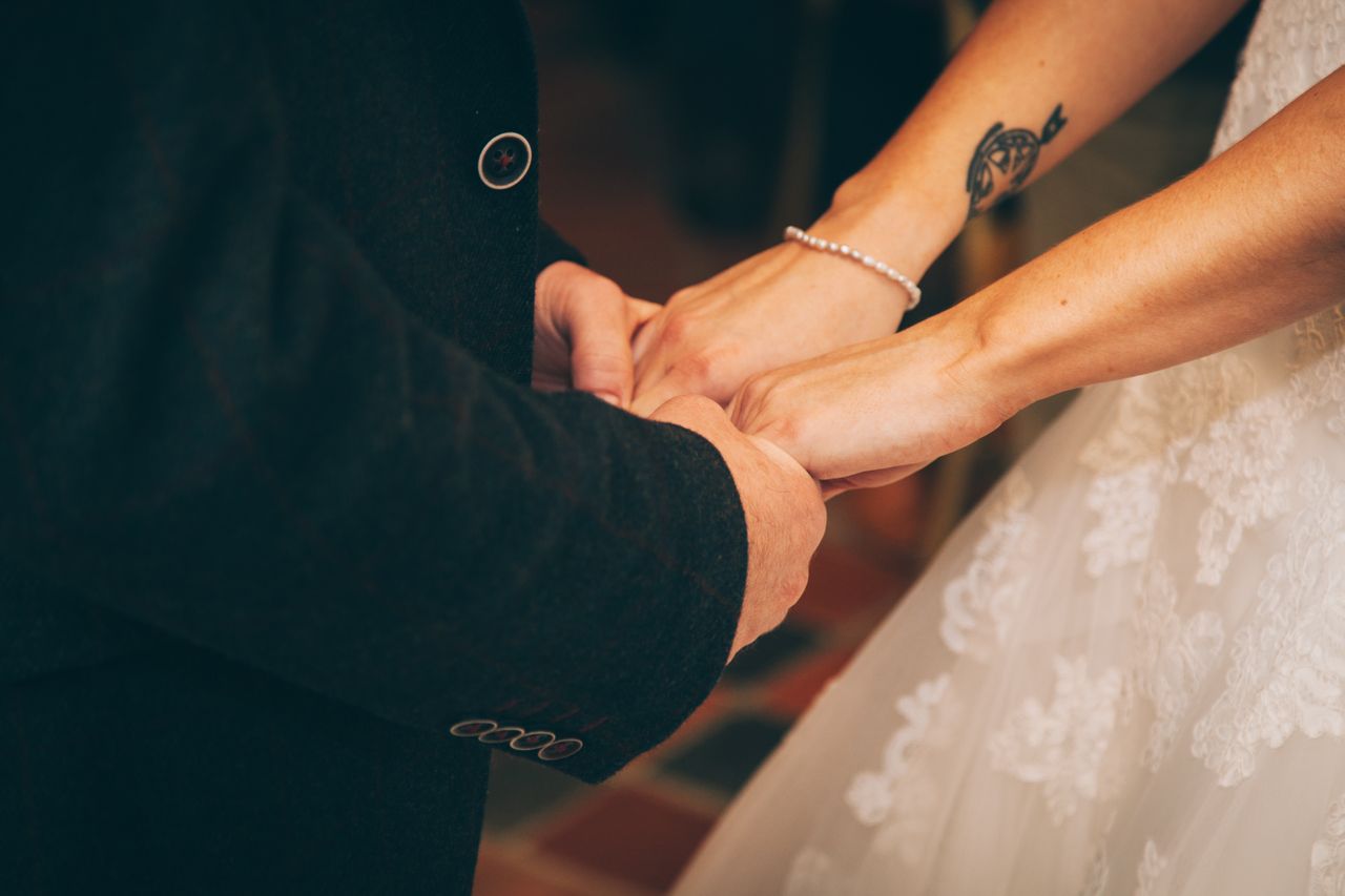 a bride and groom holding hands, the bride wearing a delicate bracelet a bride and groom holding hands, the bride wearing a delicate bracelet