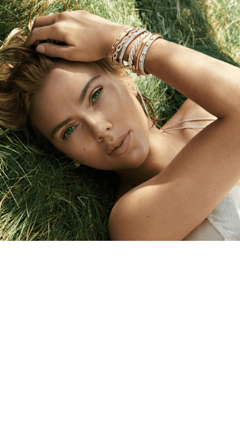 Woman lying on grass with David Yurman bracelets covering her wrist