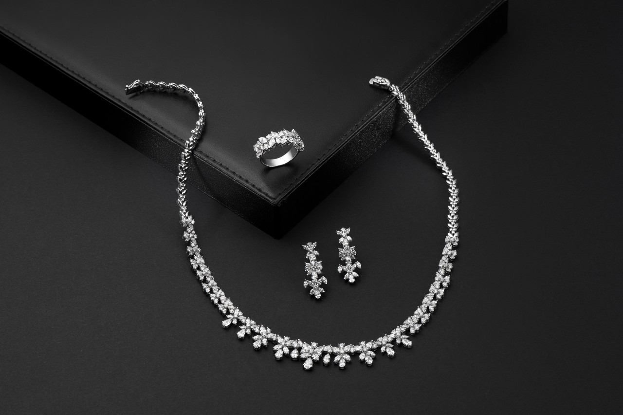 A white gold jewelry set with necklace, earrings, and a ring adorned with diamonds.