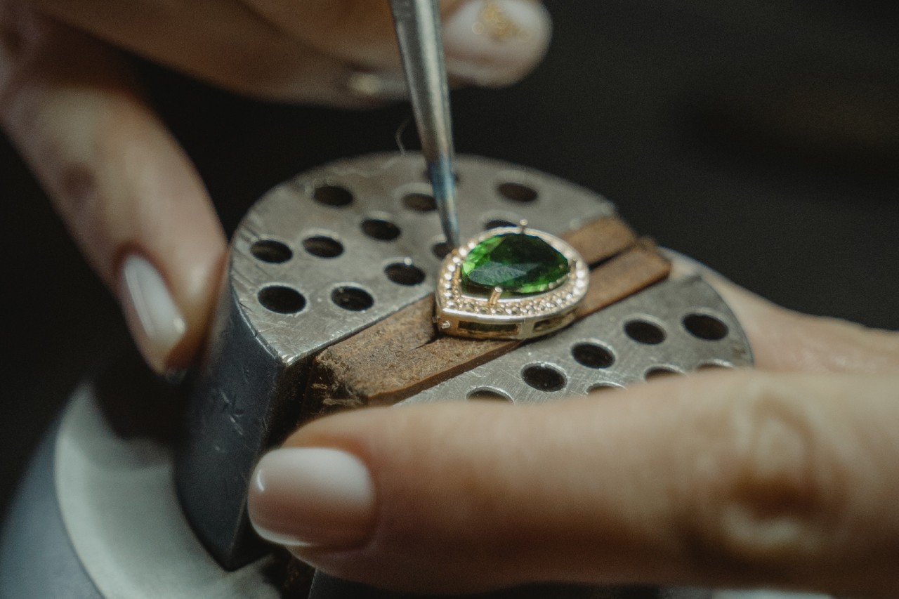 a jeweler sets a diamond into a marquise halo ring setting.