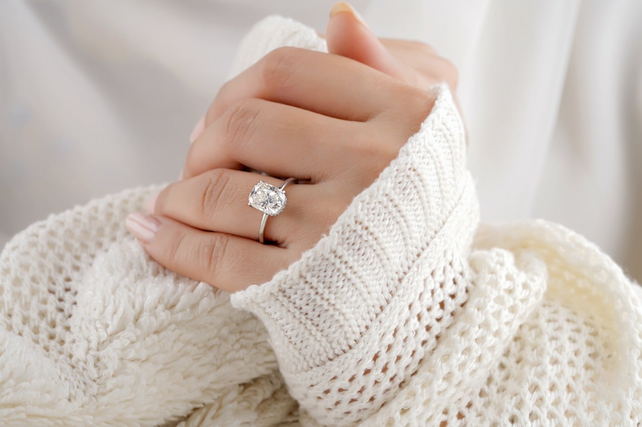 a lady’s hand wearing a simple engagement ring