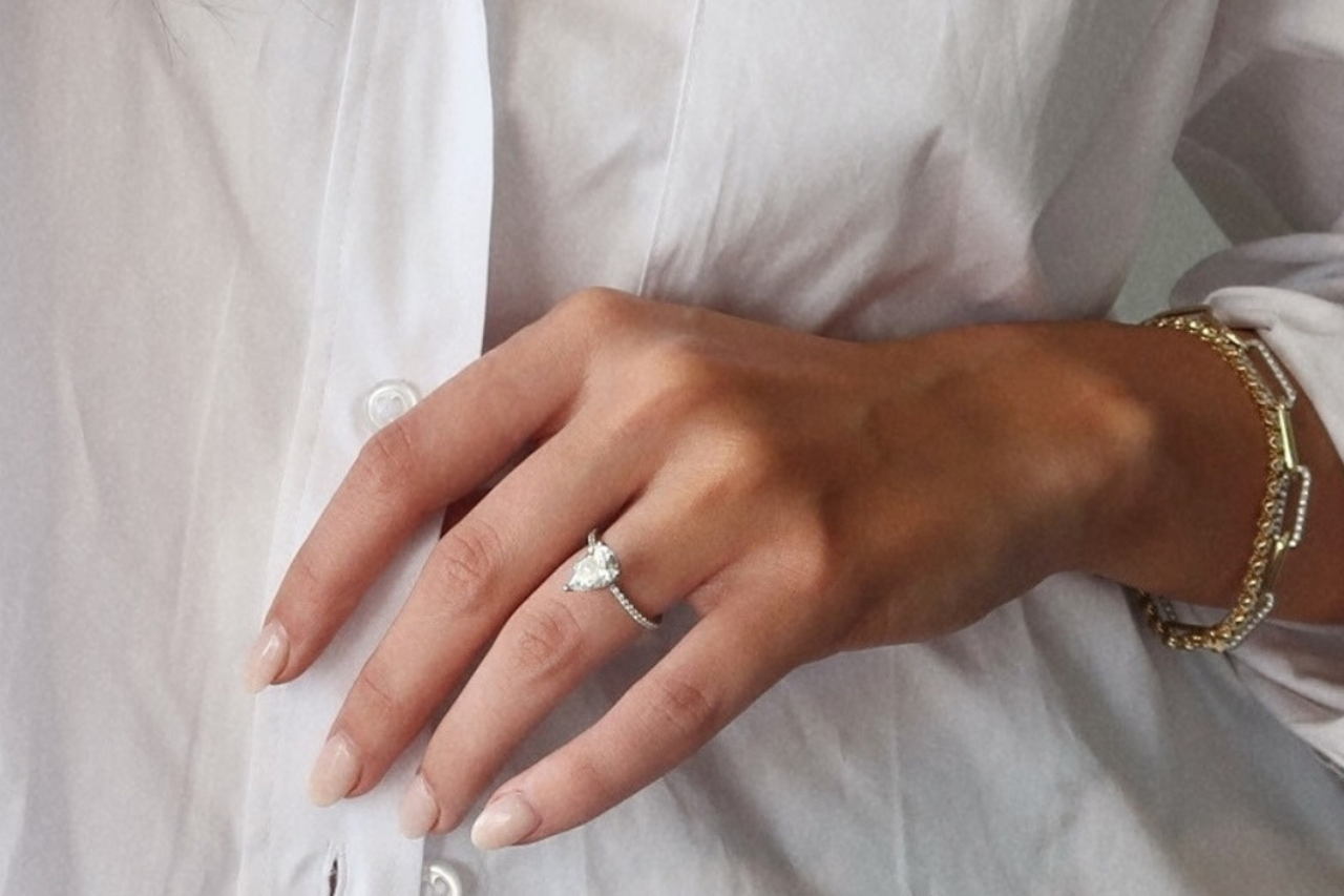 Two hands adorned with wedding and engagement rings, showcasing the union of a couple in formal attire Two hands adorned with wedding and engagement rings, showcasing the union of a couple in formal attire