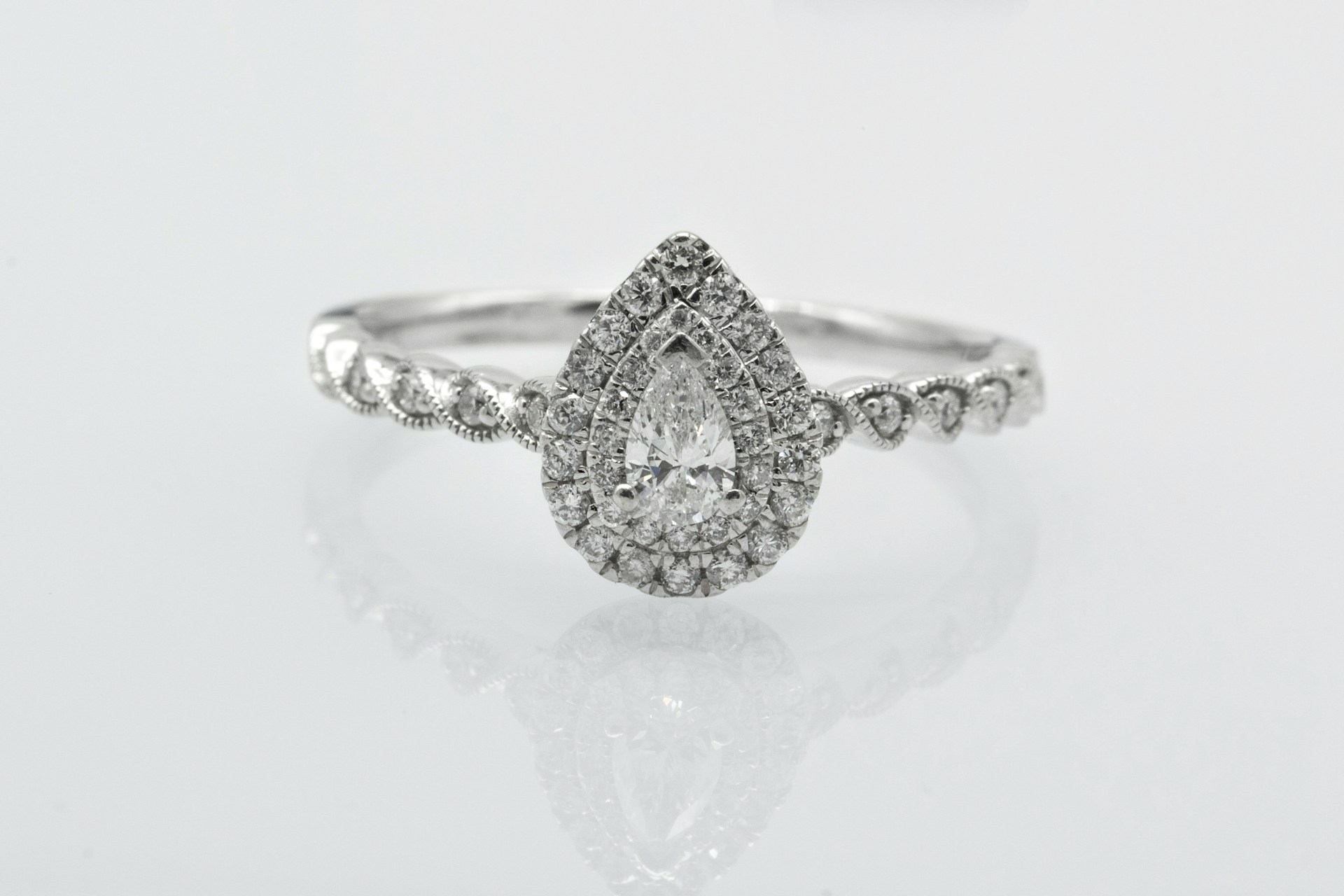 a pear shape engagement ring with a double halo and side stones