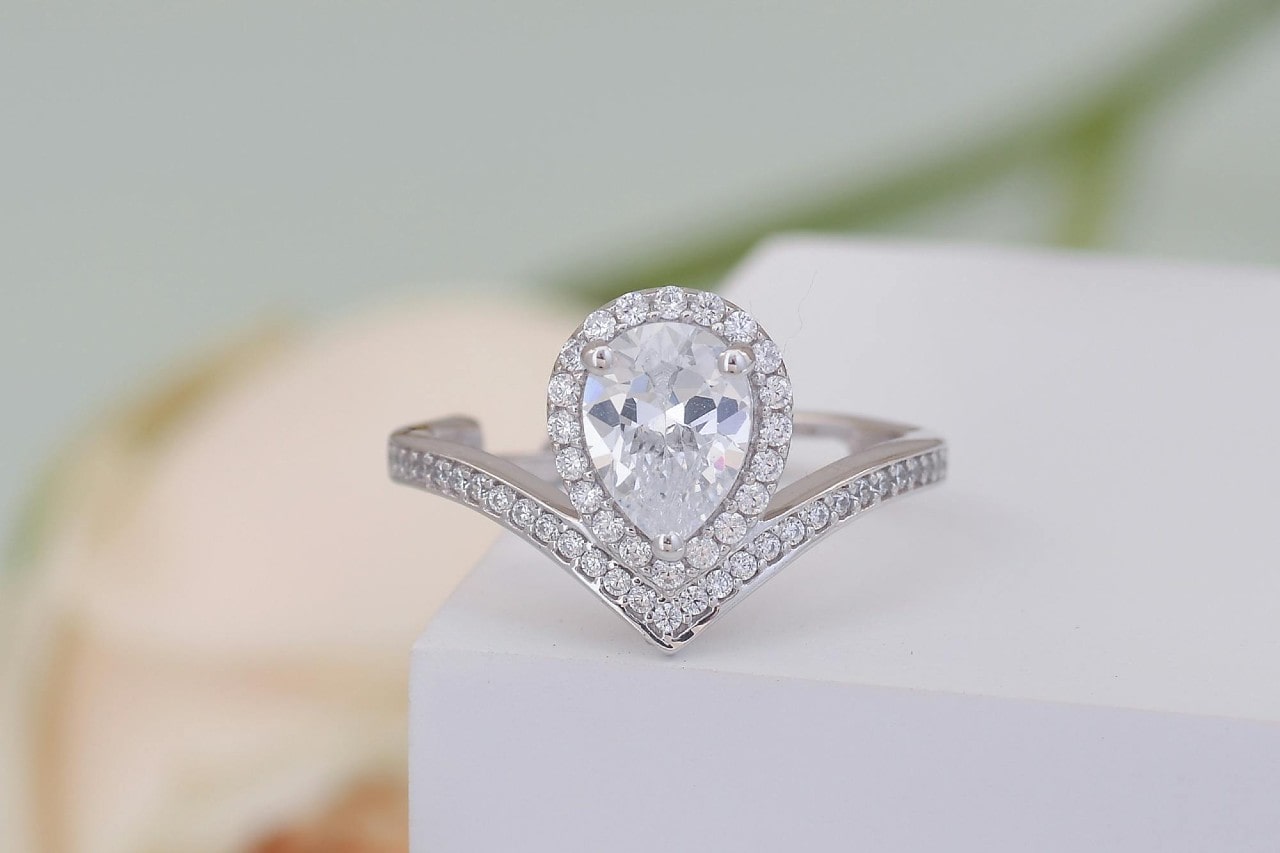 a pear shape halo engagement ring with a curved band